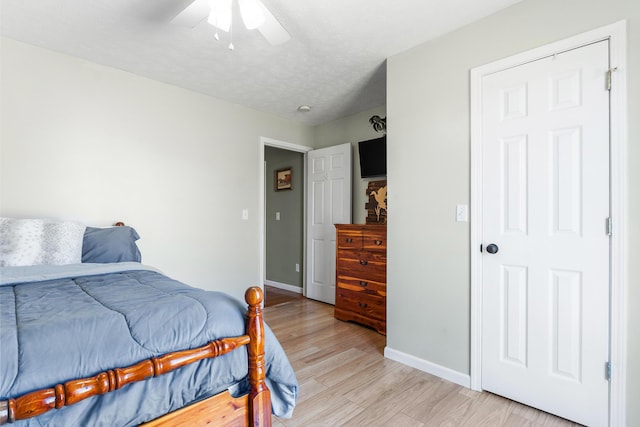 bedroom featuring a ceiling fan, light wood-style floors, baseboards, and a textured ceiling