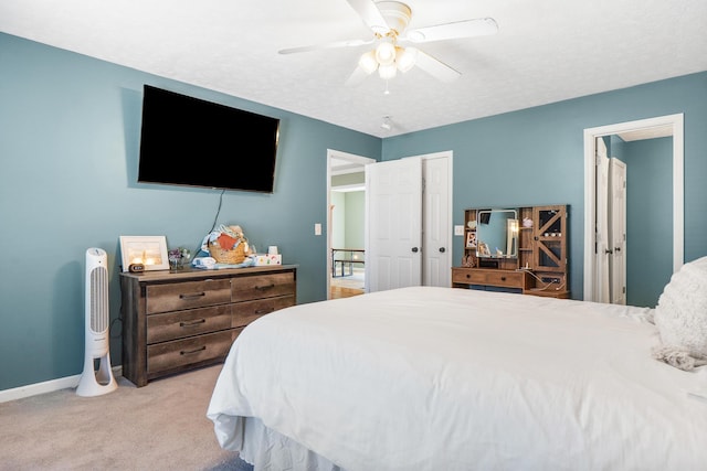 bedroom featuring baseboards, light carpet, a closet, a textured ceiling, and a ceiling fan