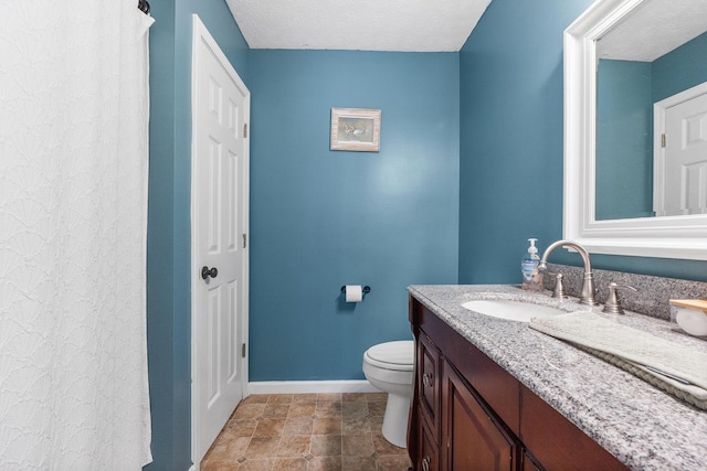 bathroom with baseboards, toilet, vanity, and a textured ceiling