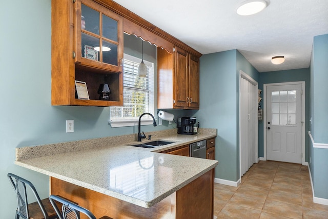 kitchen featuring a breakfast bar, a peninsula, a sink, glass insert cabinets, and brown cabinets