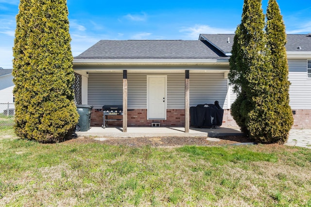 back of house with a yard, brick siding, and a shingled roof