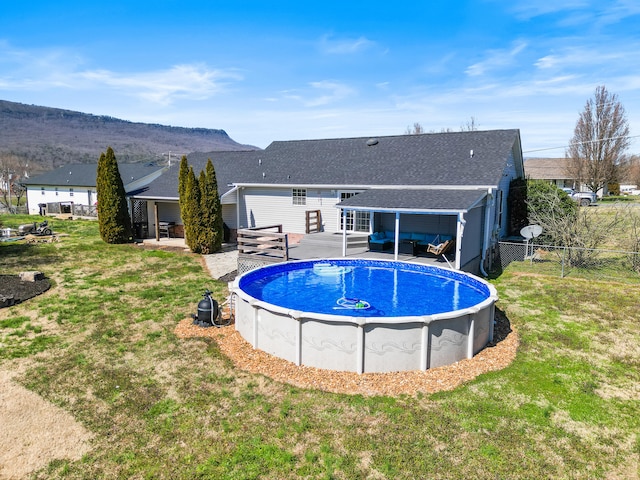 outdoor pool featuring an outdoor living space, a lawn, a deck, and fence