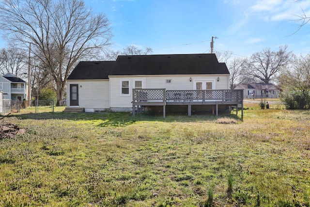 rear view of property featuring a wooden deck, a yard, and fence