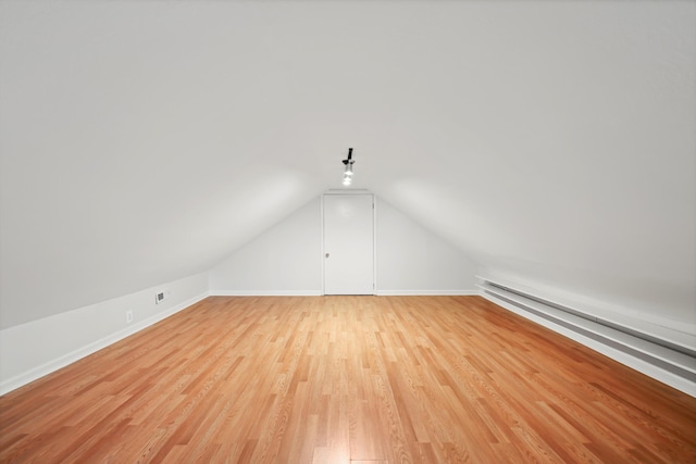 bonus room featuring baseboard heating, baseboards, light wood-style floors, and vaulted ceiling