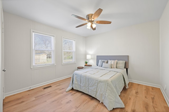 bedroom with light wood-style flooring, baseboards, visible vents, and ceiling fan