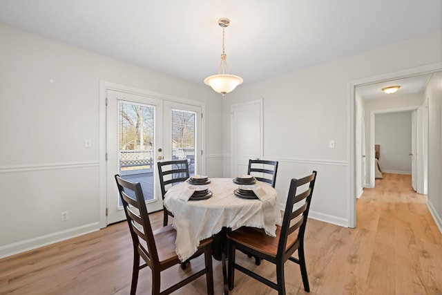 dining space featuring french doors, baseboards, and light wood finished floors