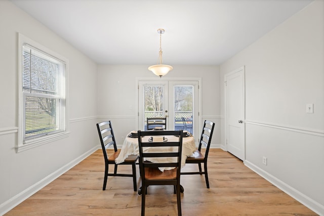 dining space with french doors, baseboards, and light wood-style flooring