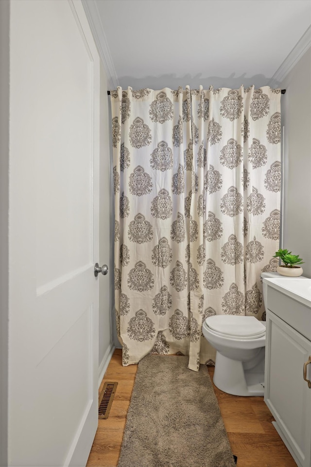 bathroom featuring toilet, wood finished floors, visible vents, and ornamental molding