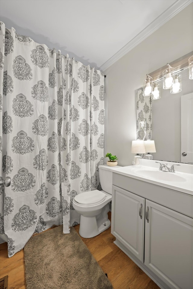 full bathroom with toilet, curtained shower, wood finished floors, crown molding, and vanity