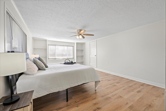 bedroom with ceiling fan, light wood-style flooring, baseboards, and a textured ceiling