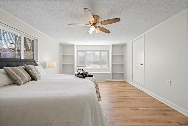 bedroom featuring light wood finished floors, multiple windows, a textured ceiling, and crown molding