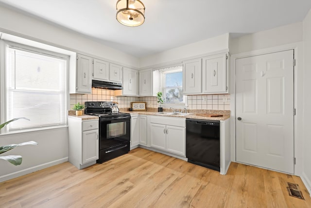 kitchen featuring visible vents, black appliances, light wood-style flooring, under cabinet range hood, and a sink