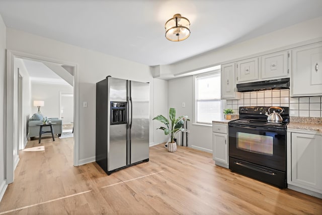 kitchen with black range with electric stovetop, under cabinet range hood, light countertops, decorative backsplash, and stainless steel fridge