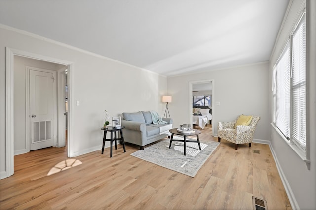 living area with visible vents, wood finished floors, and crown molding