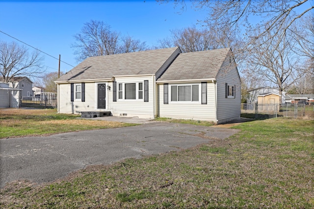 view of front of house featuring a front yard, fence, and a shingled roof