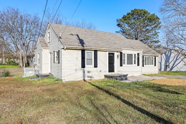 view of front facade with a front yard, fence, and roof with shingles