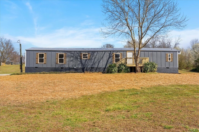 view of front of property with a standing seam roof, board and batten siding, metal roof, a front yard, and crawl space