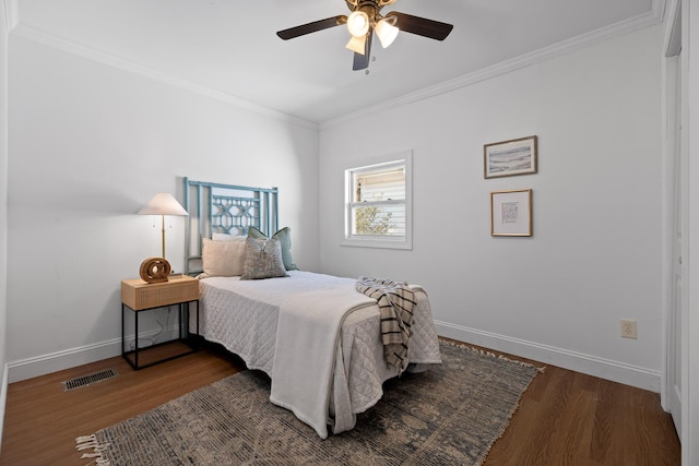 bedroom with visible vents, baseboards, wood finished floors, and ornamental molding