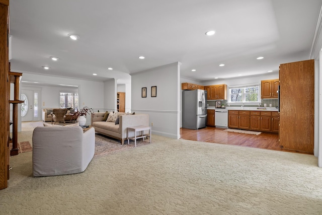 living room featuring crown molding, recessed lighting, light colored carpet, and baseboards