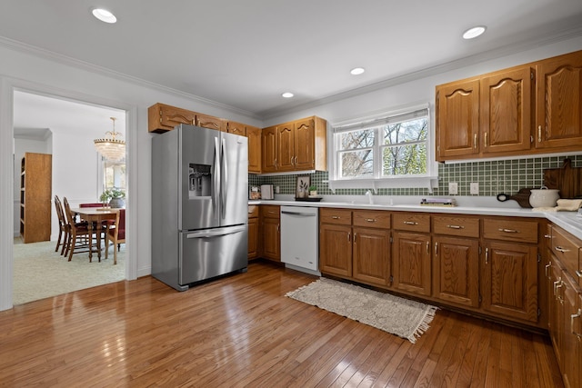 kitchen featuring brown cabinets, dishwasher, stainless steel refrigerator with ice dispenser, and ornamental molding