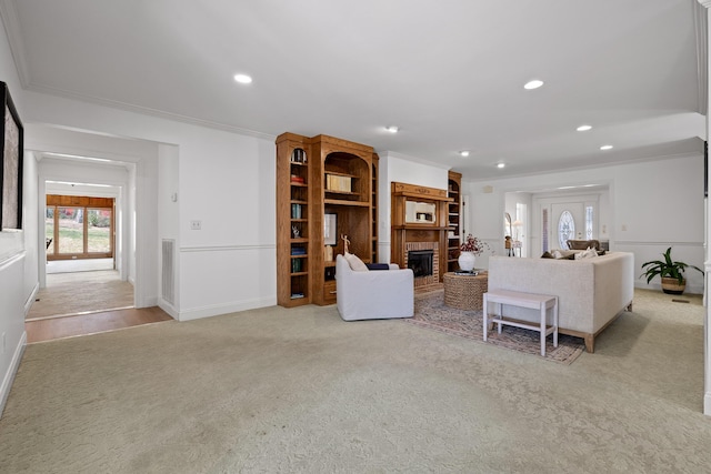 carpeted living room featuring visible vents, baseboards, ornamental molding, recessed lighting, and a fireplace