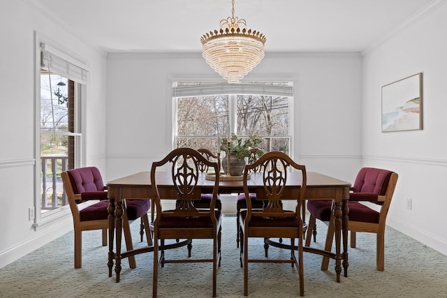 dining area with an inviting chandelier, carpet flooring, baseboards, and ornamental molding