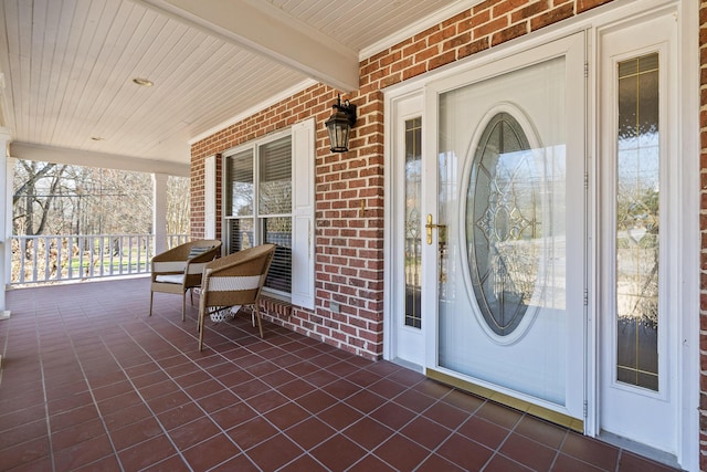 property entrance featuring brick siding and a porch