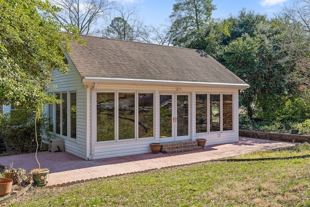 rear view of property featuring a patio, entry steps, and a shingled roof