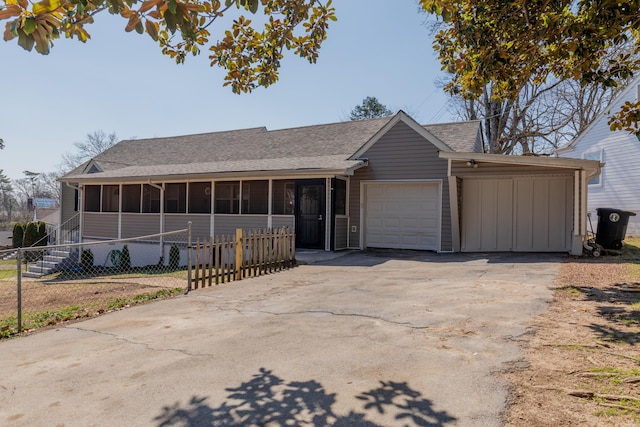 view of front of property with driveway, fence, roof with shingles, a sunroom, and a garage