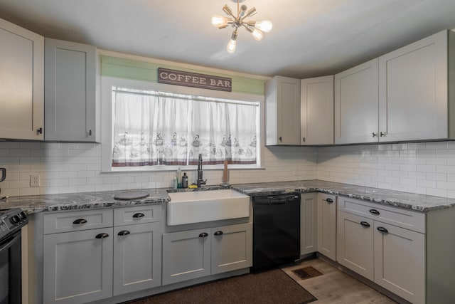 kitchen with a sink, stone countertops, tasteful backsplash, and black appliances