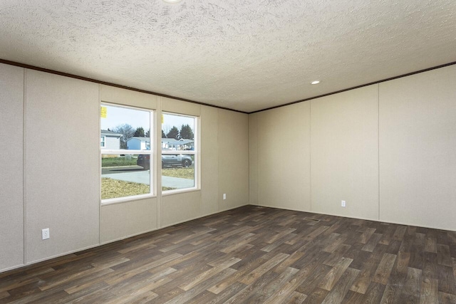 spare room with a decorative wall, a textured ceiling, crown molding, and wood finished floors