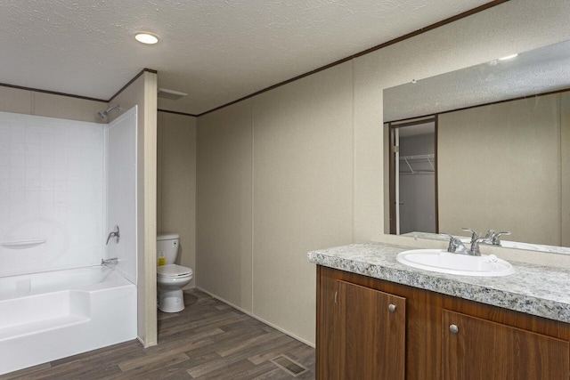 bathroom featuring vanity, wood finished floors,  shower combination, a textured ceiling, and toilet