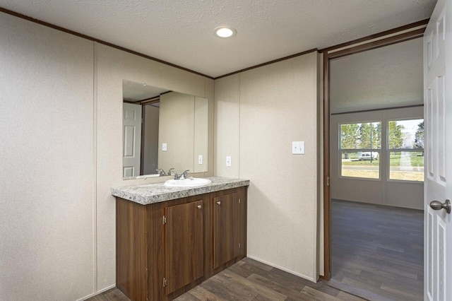 bathroom with vanity, crown molding, wood finished floors, and a textured ceiling