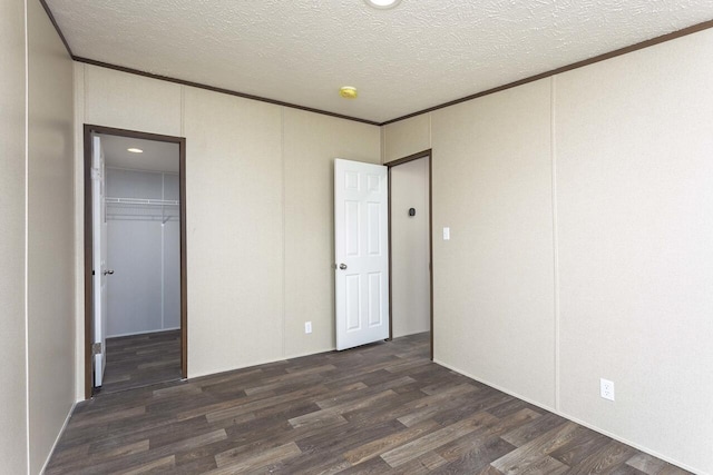 unfurnished bedroom with dark wood finished floors, crown molding, a closet, and a textured ceiling