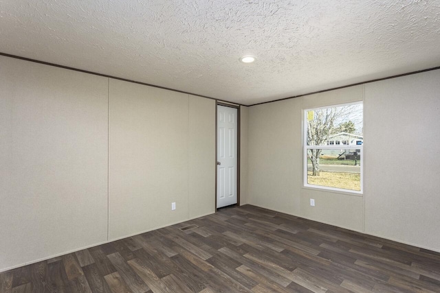 spare room featuring dark wood-style flooring and a textured ceiling