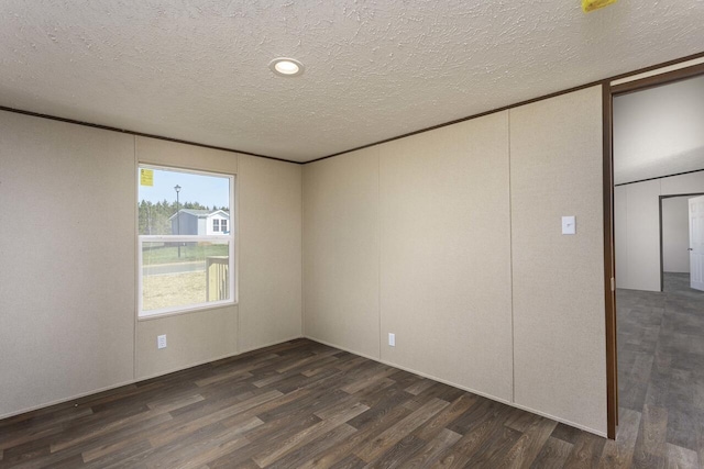 empty room with dark wood finished floors and a textured ceiling