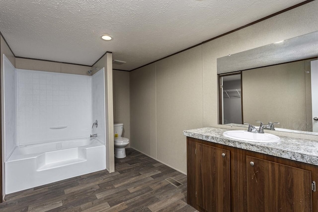 full bath with toilet, vanity, shower / bathtub combination, wood finished floors, and a textured ceiling