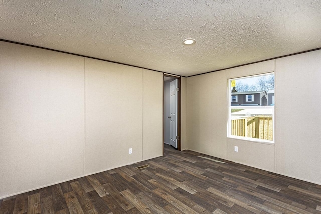 empty room with dark wood-type flooring and a textured ceiling