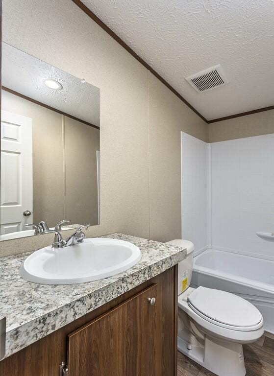 bathroom with vanity, crown molding, visible vents, and a textured ceiling