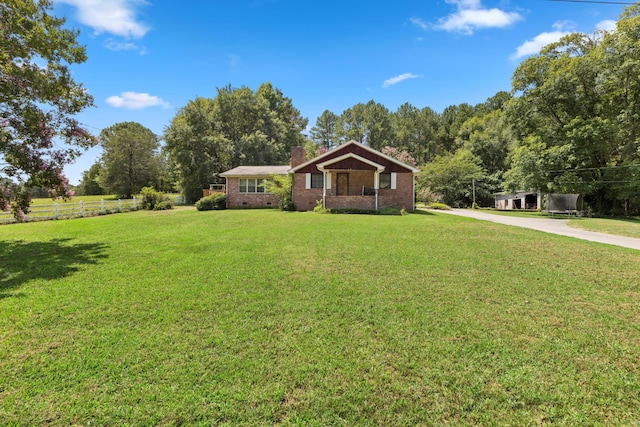 ranch-style home with a front lawn, fence, brick siding, and a chimney