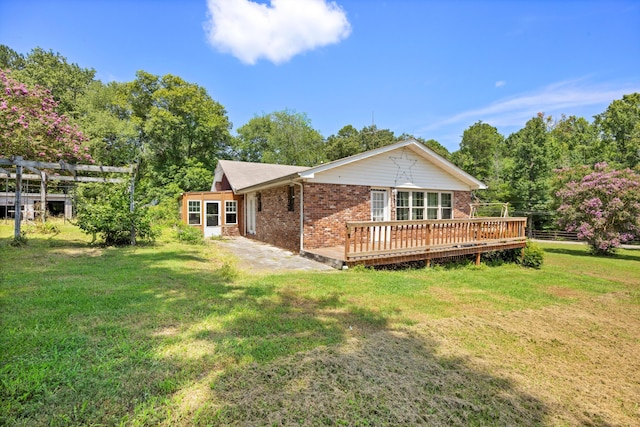 back of property with brick siding, a wooden deck, and a yard