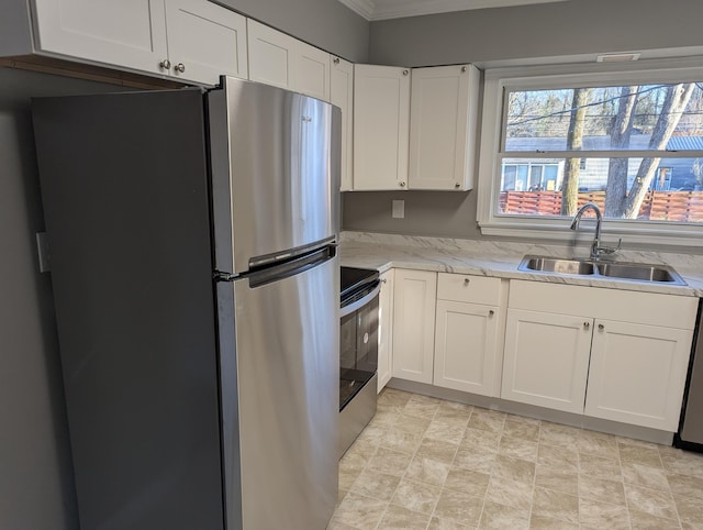 kitchen featuring a sink, light stone counters, appliances with stainless steel finishes, and white cabinetry