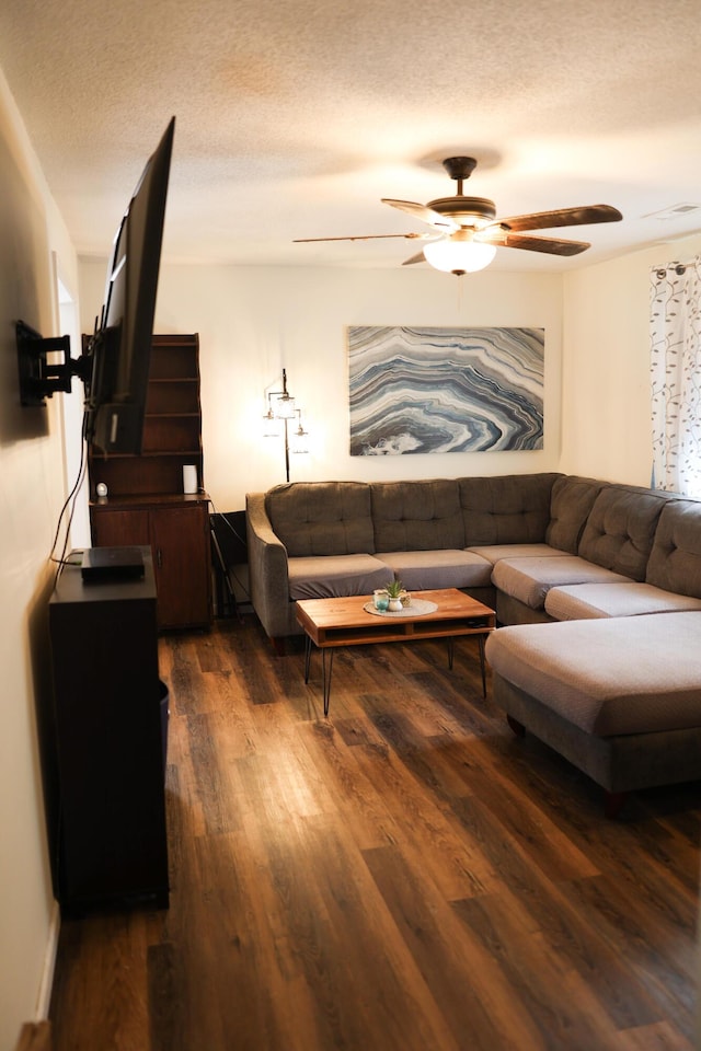 living room with a textured ceiling, dark wood-style floors, and a ceiling fan