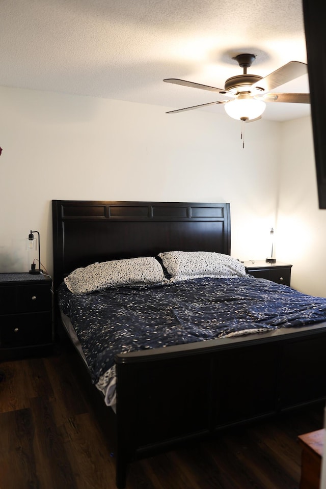 bedroom with dark wood-type flooring, a ceiling fan, and a textured ceiling