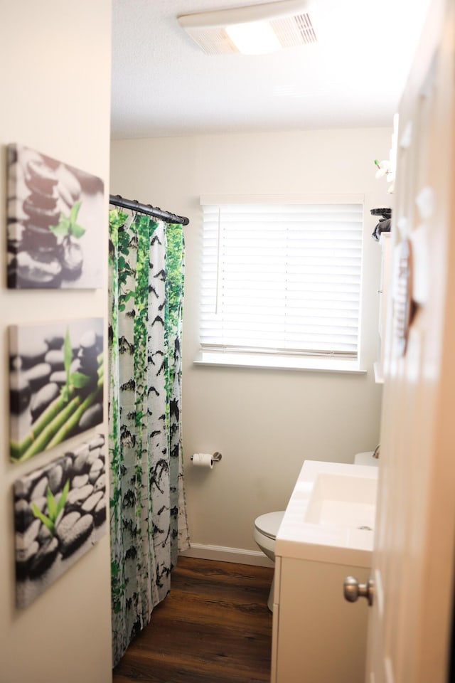 full bath with vanity, wood finished floors, baseboards, curtained shower, and toilet