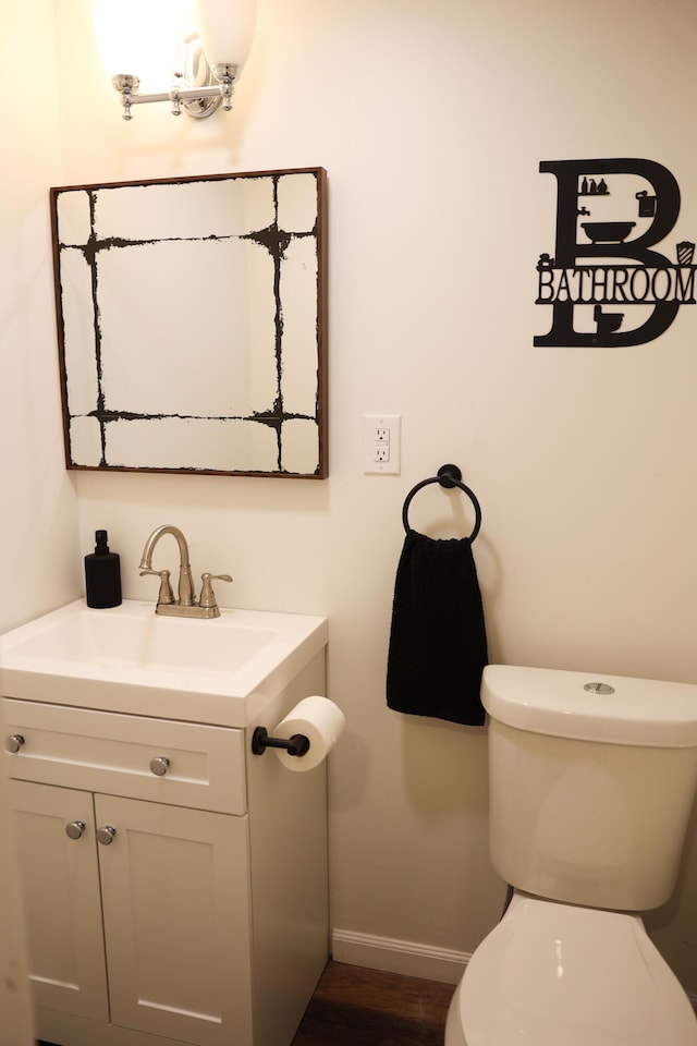 bathroom with toilet, vanity, and baseboards