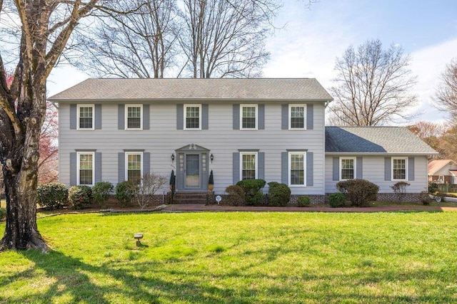 colonial inspired home with a shingled roof and a front lawn