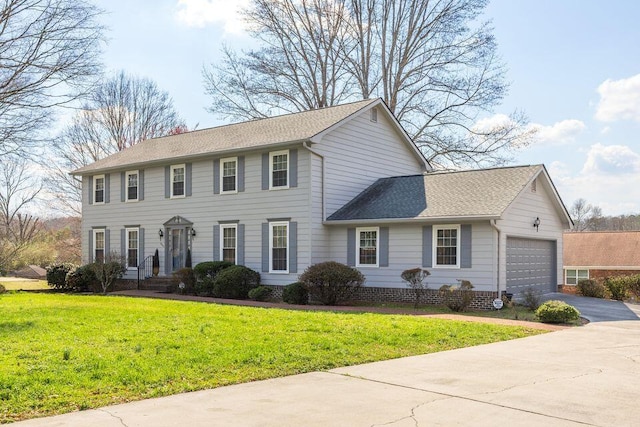 colonial-style house with driveway, an attached garage, a front lawn, and roof with shingles