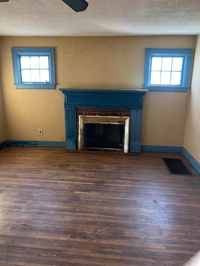 details featuring wood finished floors, baseboards, visible vents, a textured ceiling, and a brick fireplace