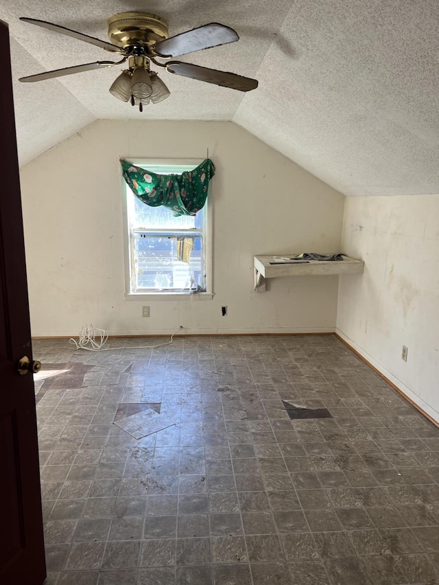 bonus room featuring baseboards, a textured ceiling, lofted ceiling, and a ceiling fan